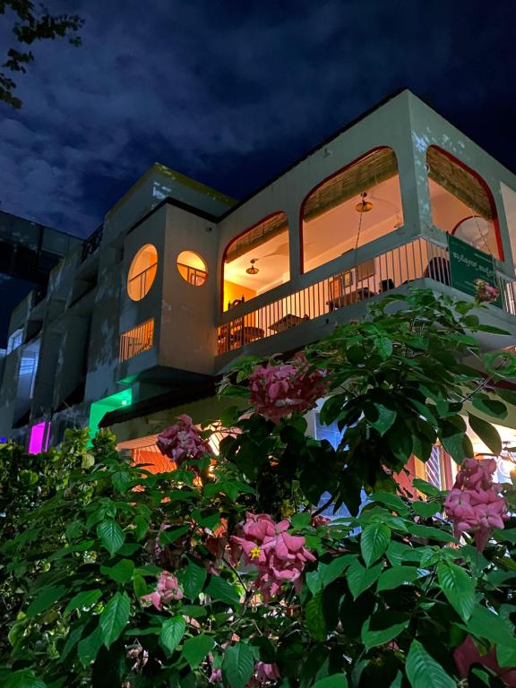 un edificio con flores rosas delante de él en Crossroads Hostel 1980, en Mysore