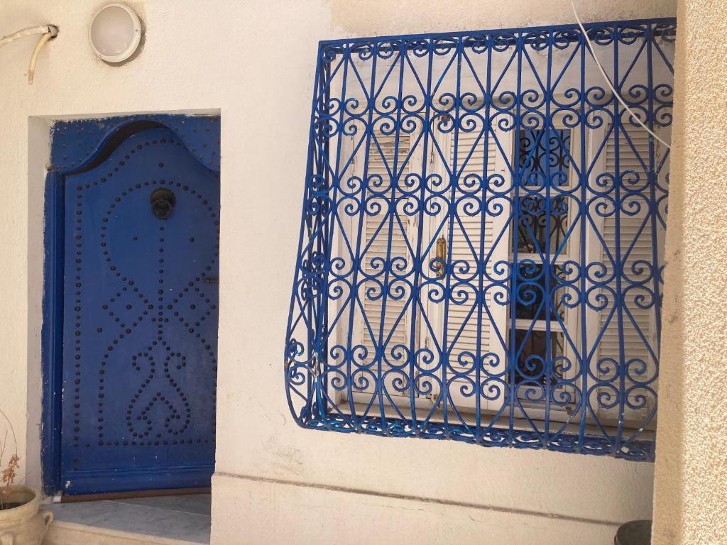 La Marsa Maison avec jardin, terrasse parking Wifi Illimité في المرسى: بوابة زرقاء على جدار أبيض بجوار باب