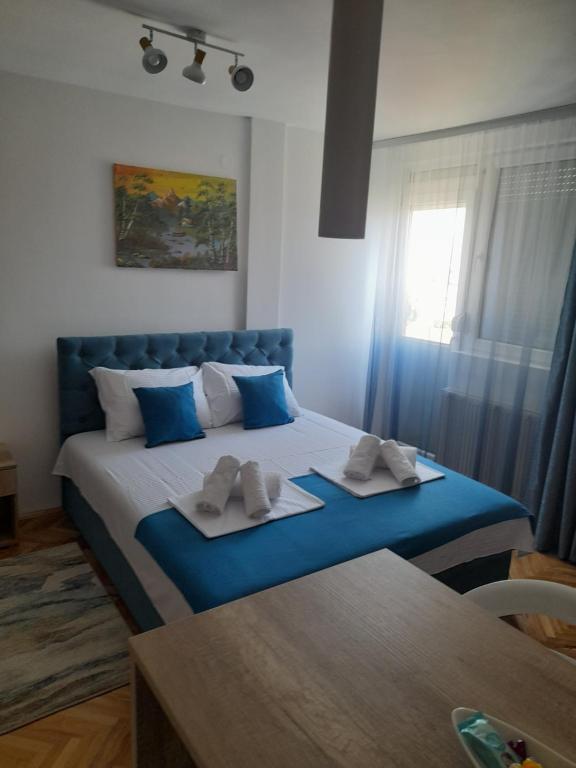 a bedroom with a blue bed with towels on it at Holiday apartament 3 in Niš