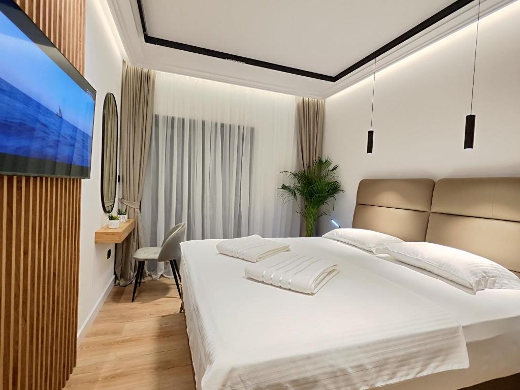 een slaapkamer met een groot wit bed en een bureau bij AMD Premium rooms Budva in Budva