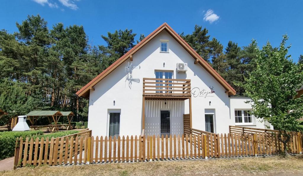 uma casa branca com uma cerca de madeira em Ostoja em Ostrowo