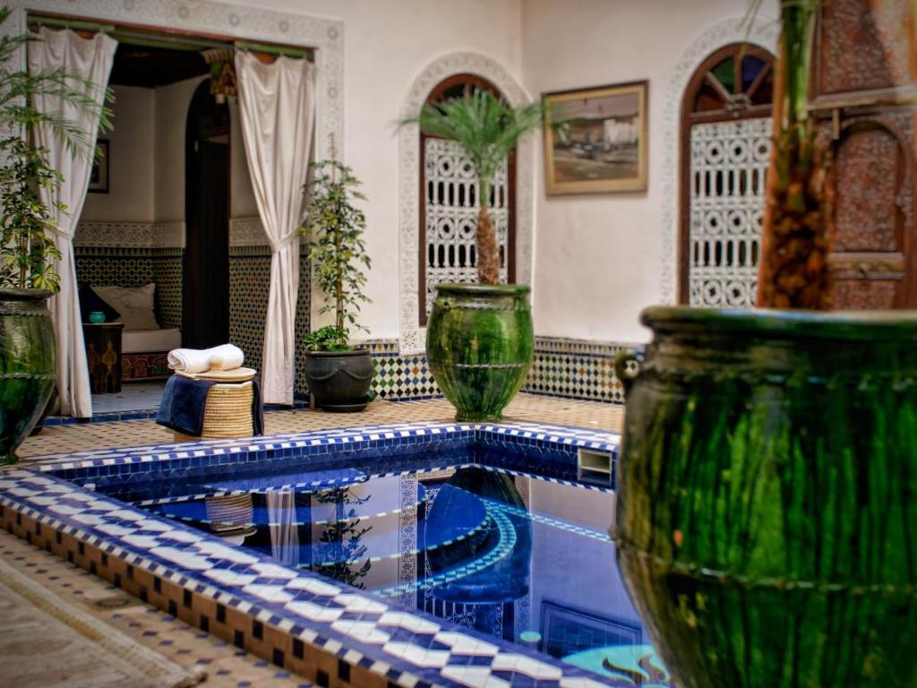 ein Schwimmbad in einem Haus mit einigen Vasen in der Unterkunft Riad Malida Marrakech in Marrakesch