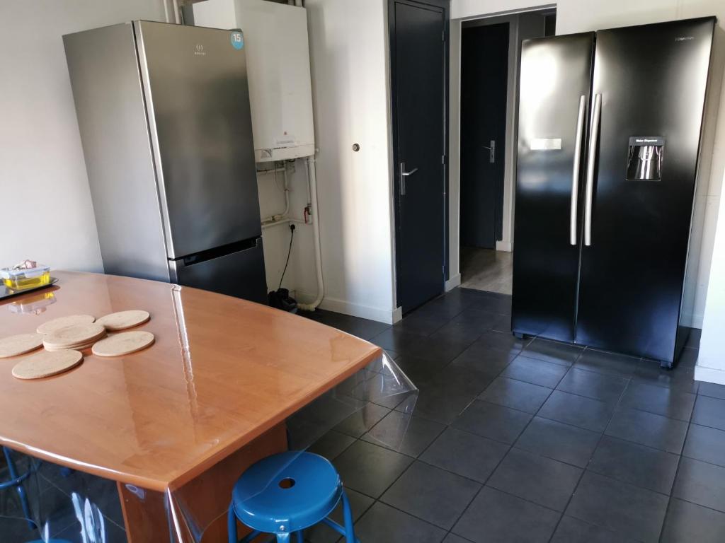 Il comprend une cuisine équipée d'une table en bois et d'un réfrigérateur. dans l'établissement Résidence Zola, au Havre