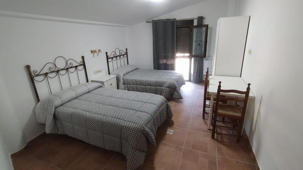Habitación con 2 camas, mesa y silla en Casa Marcelinas por habitaciones en Samper del Salz