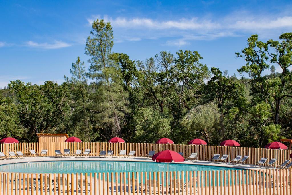 a swimming pool with chairs and red umbrellas at Huttopia Wine Country in Lower Lake