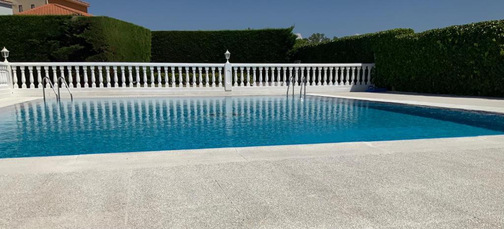 una piscina con una valla blanca y agua azul en Hotel Mozárbez Salamanca en Mozárbez