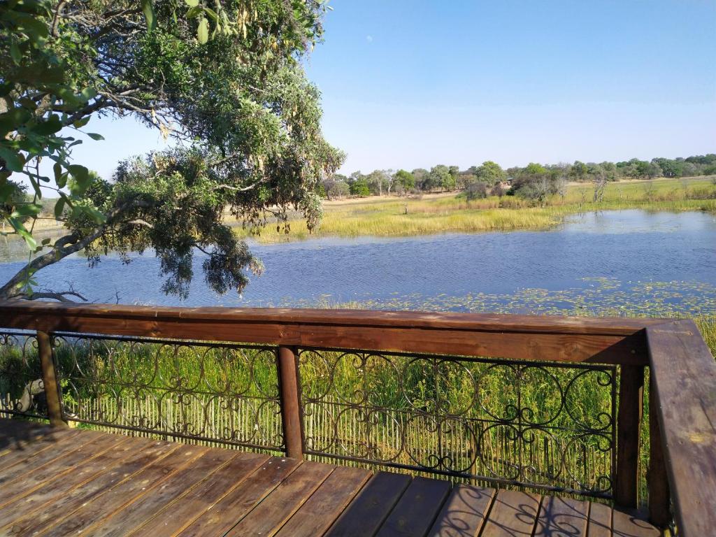 a wooden bench with a view of a river at Nako Okavango Guesthouse in Ntabis
