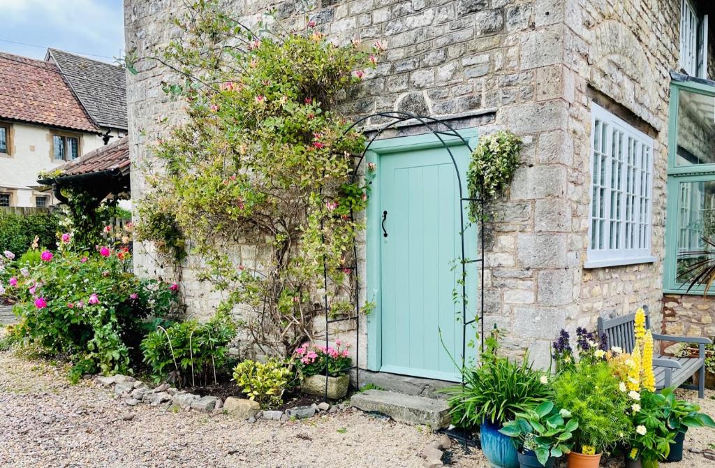 a brick building with a blue door and some flowers at The Long House in Flax Bourton