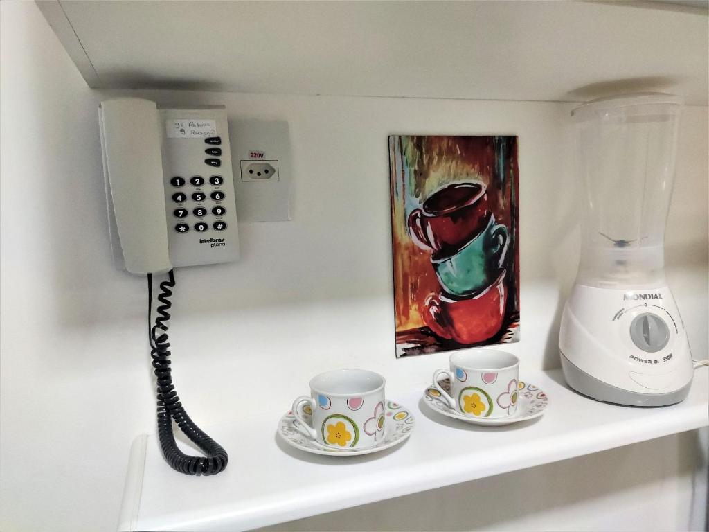 a phone and two cups on a shelf at L316 LA Apartamento aconchegante resort à beira lago in Brasilia