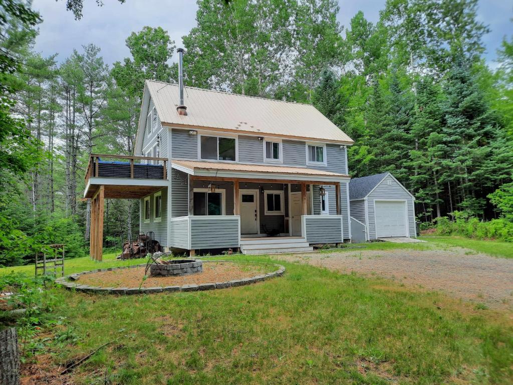 a house with a wrap around porch and a yard at 157SL peaceful forest retreat in Franconia
