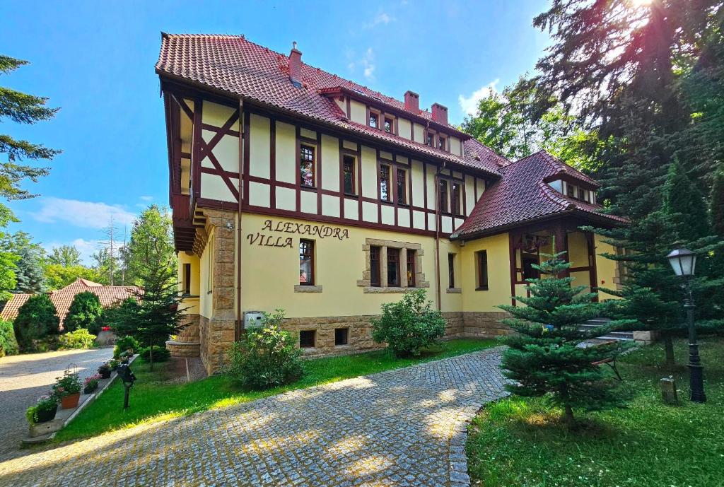 a large yellow house with a red roof at Villa Alexandra in Polanica-Zdrój