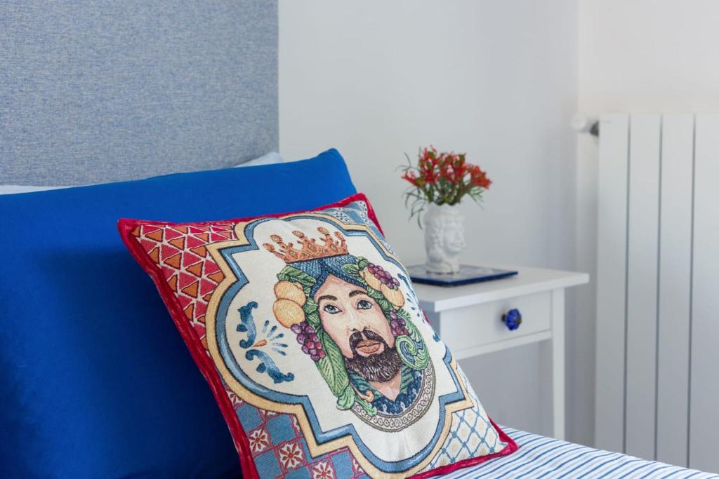 Una cama azul con una almohada con una pintura encima. en Zagara e Sirene, en Amalfi