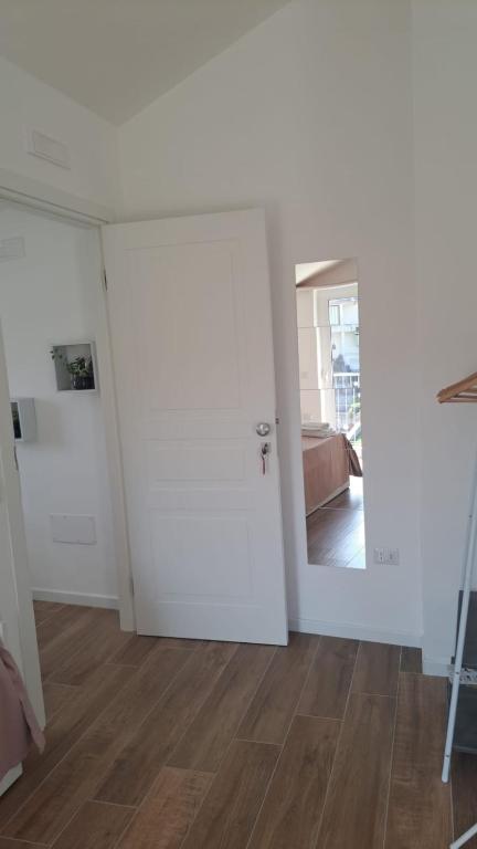 a white room with a door and a wooden floor at Nànnì guest home in Pozzovetere