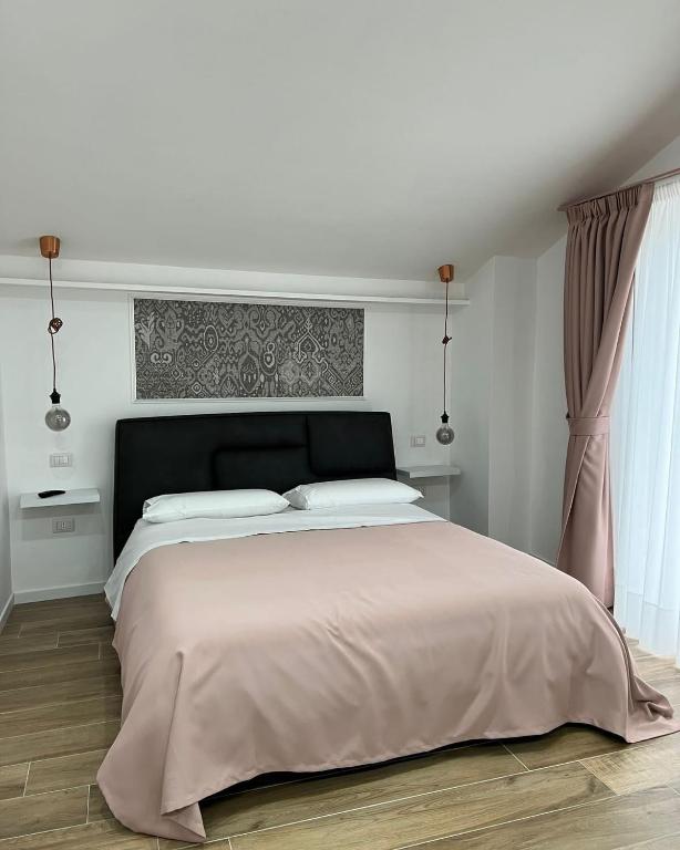 a white bedroom with a large bed with a black headboard at Nànnì guest home in Pozzovetere