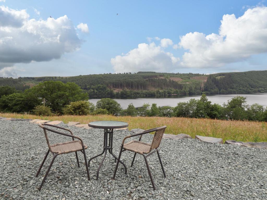 une table et deux chaises assises à côté d'un lac dans l'établissement Llety Dewi, à Oswestry