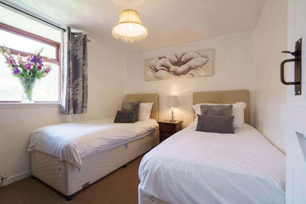 dwa łóżka w pokoju z oknem w obiekcie Jane Welsh Cottage w mieście Thornhill