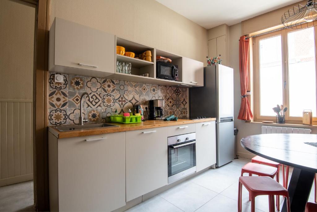 une cuisine avec des armoires blanches et une table dans l'établissement Maison cosy 4chambres 3SDB proche toute commodité, à Croix