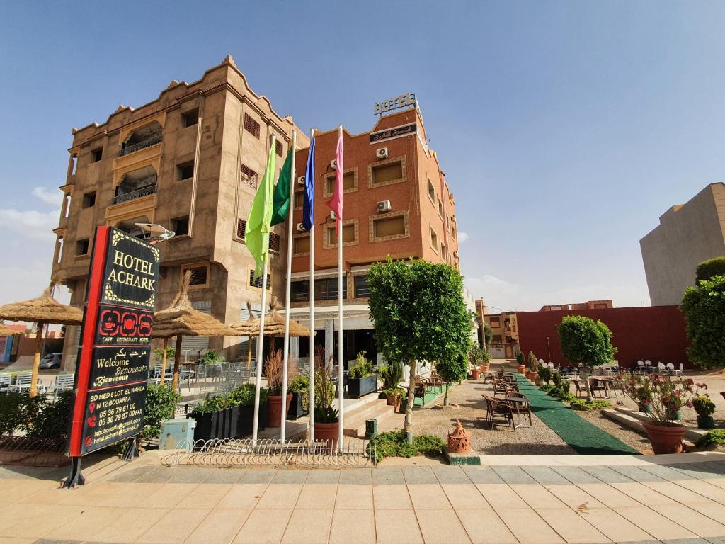 a building with flags in front of it on a street at Hotel Achark in Bou Arfa
