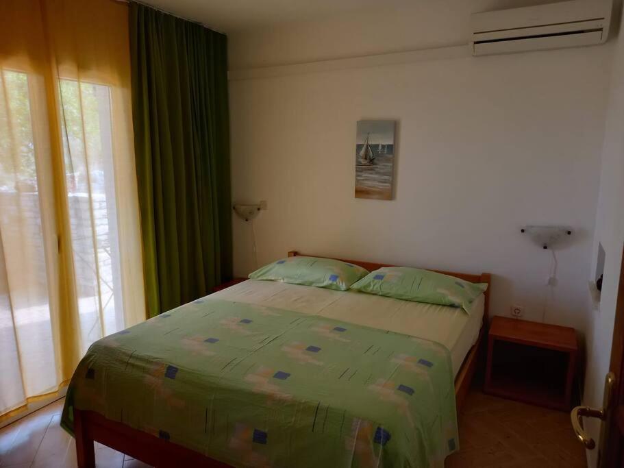 - une chambre avec un lit doté de rideaux verts et d'une fenêtre dans l'établissement Apartments Belvedere - A3, à Nečujam