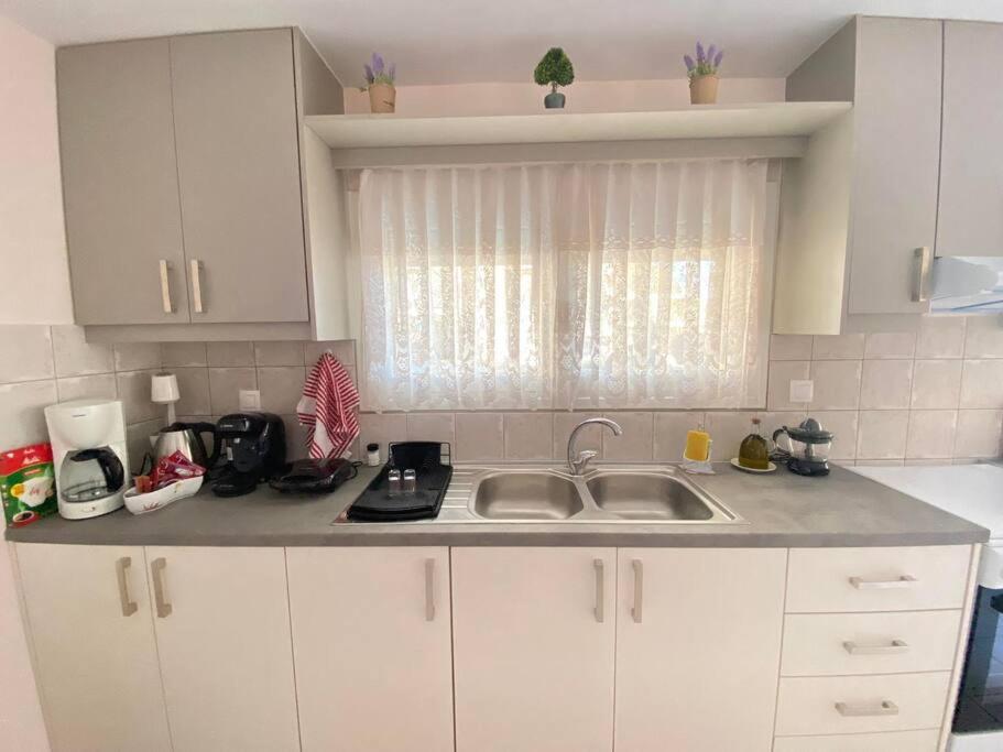 a kitchen with white cabinets and a sink at Maria's Modern Apartment , Monemvasia in Monemvasia