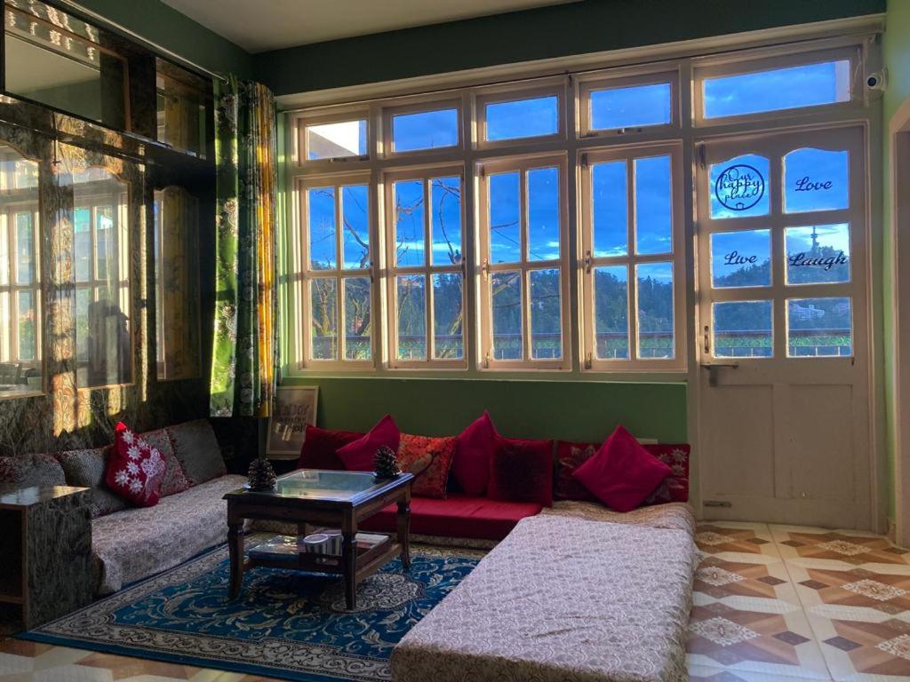 a living room with a couch and a large window at Zu-Zu Hostels in Shimla