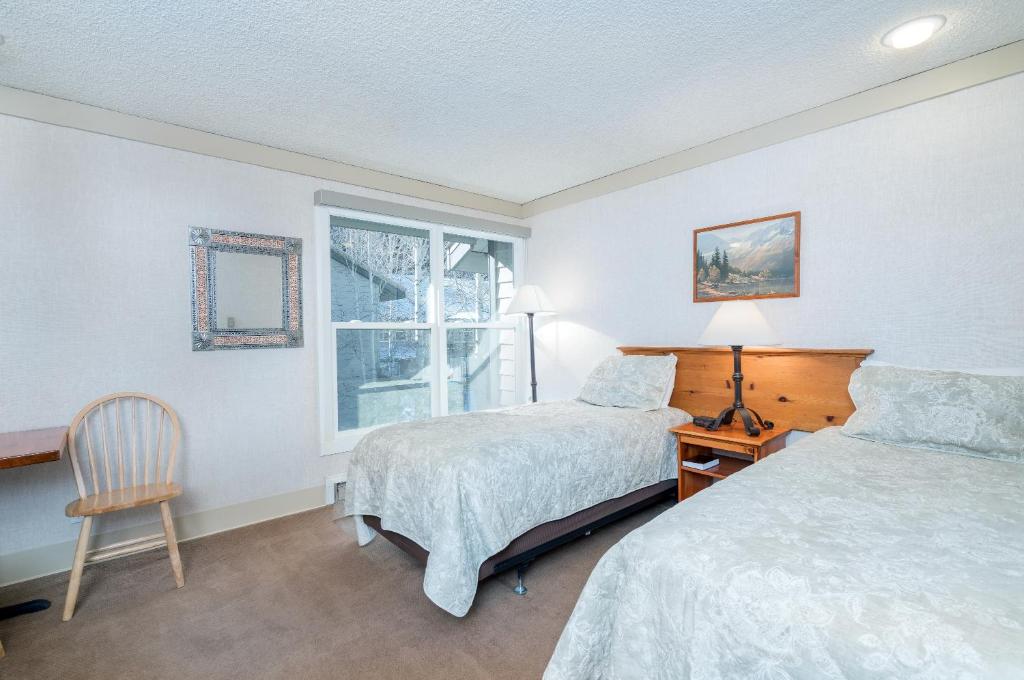 a bedroom with two beds and a chair and a window at Mountainside Inn 214 Hotel Room in Telluride