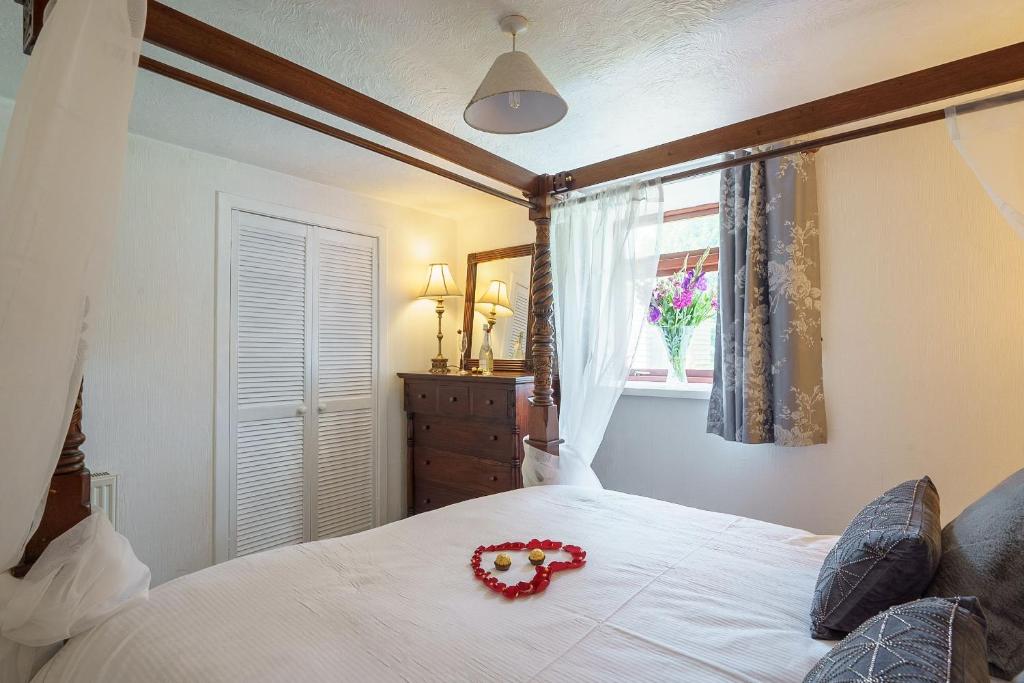 a bedroom with a white bed with a red flower on it at Dalgarnock Cottage in Thornhill