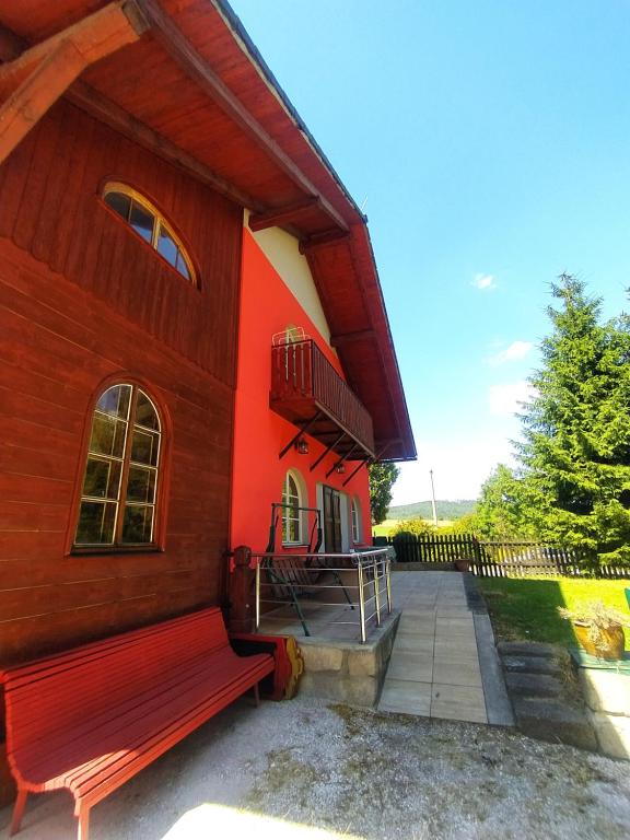 a red building with a bench in front of it at Haškovna - tradice zájezdního hostince u Prachovských skal in Ohaveč