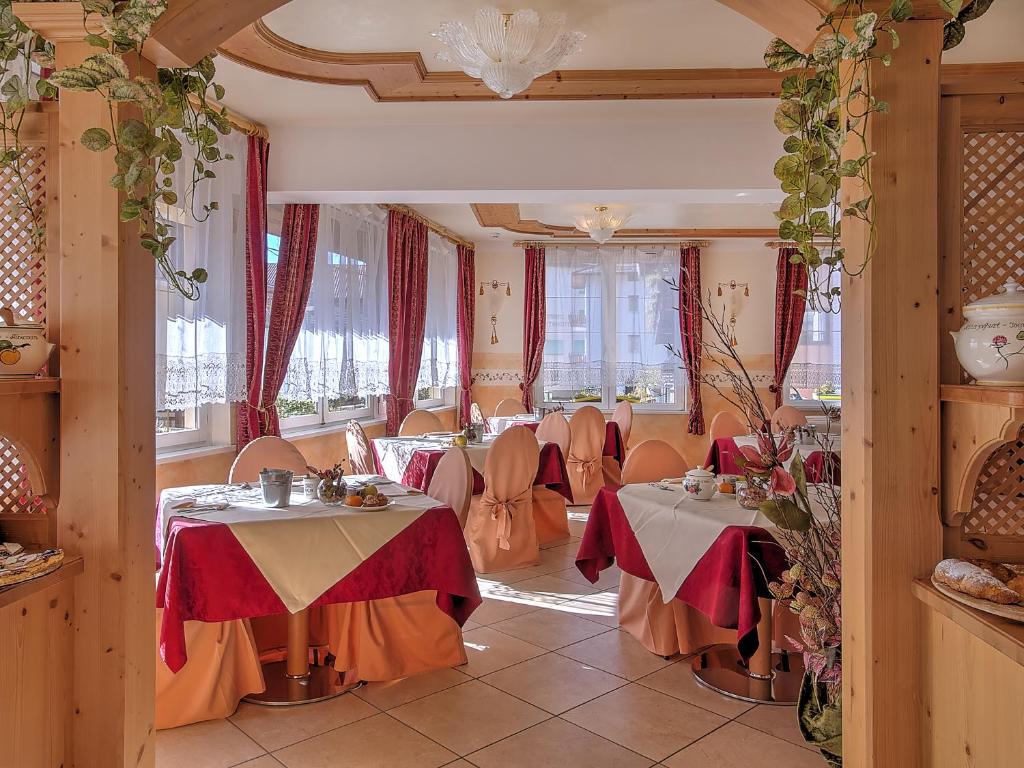 ein Restaurant mit Tischen und Stühlen in einem Raum in der Unterkunft Al Posta Hotel 1899 in Baselga di Pinè