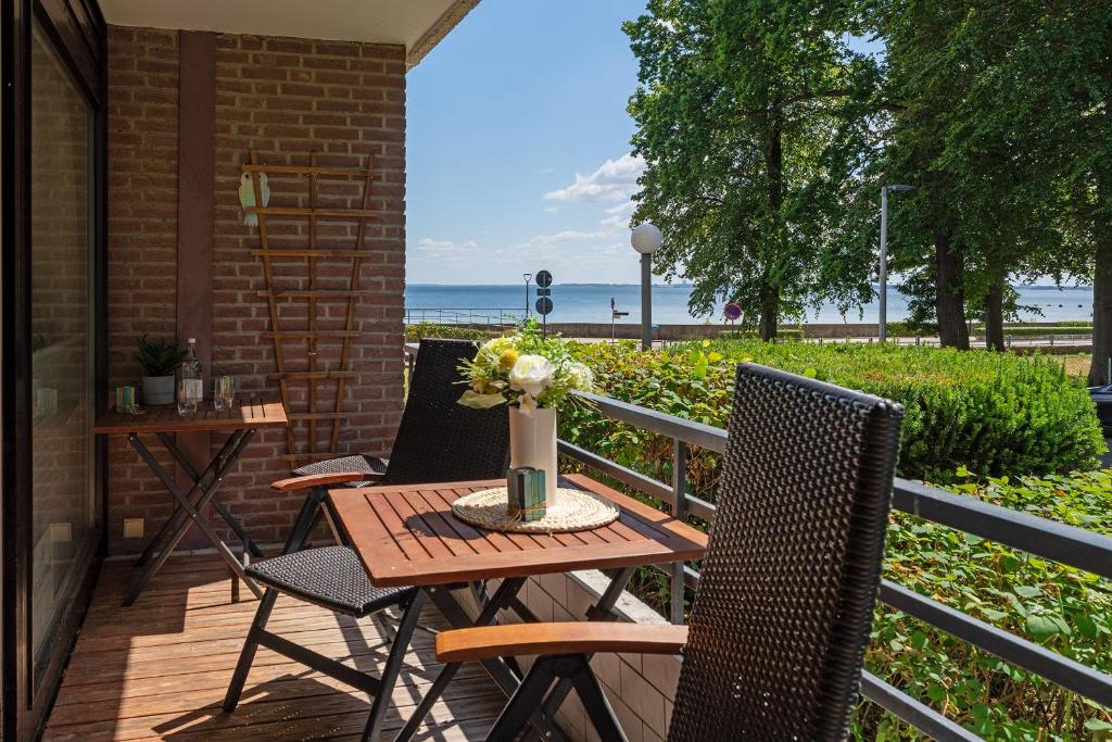 une terrasse avec une table et des chaises et la plage dans l'établissement Maretimo Meerblick, à Haffkrug