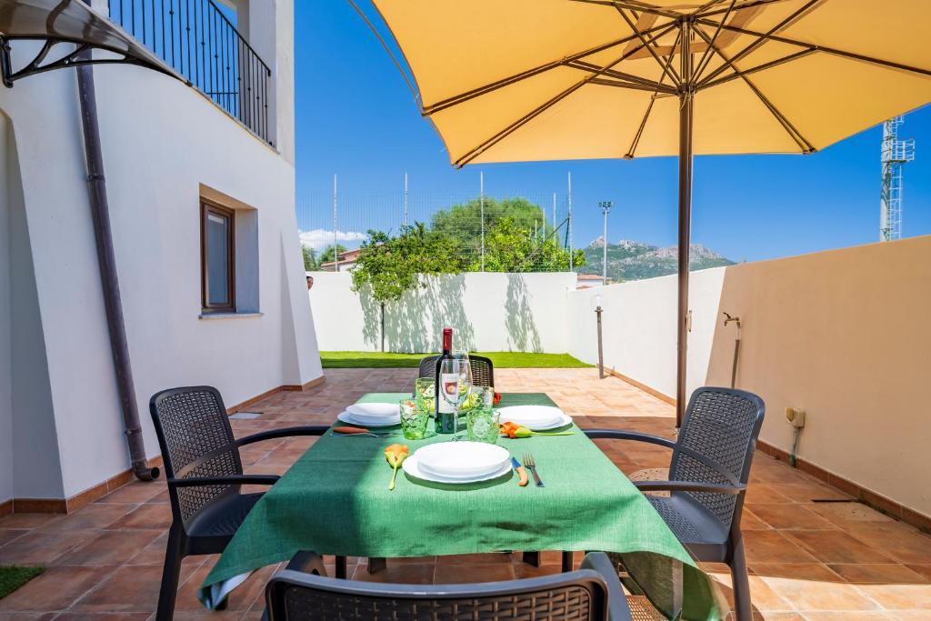 uma mesa com uma toalha de mesa verde e um guarda-chuva amarelo em 5 - Relax e comfort in casa con giardino - Sa Crai Apartments Sardinian Experience em Lotzorai
