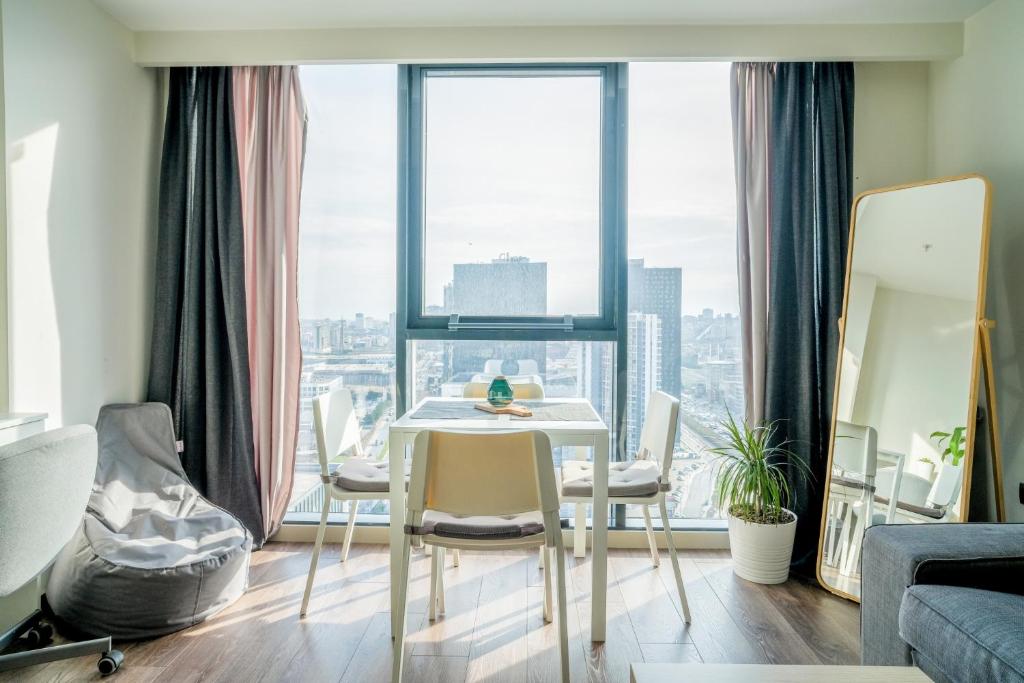 een woonkamer met een tafel en stoelen voor een raam bij Flat w City View Wall 5 min to Mall of Istanbul in Istanbul