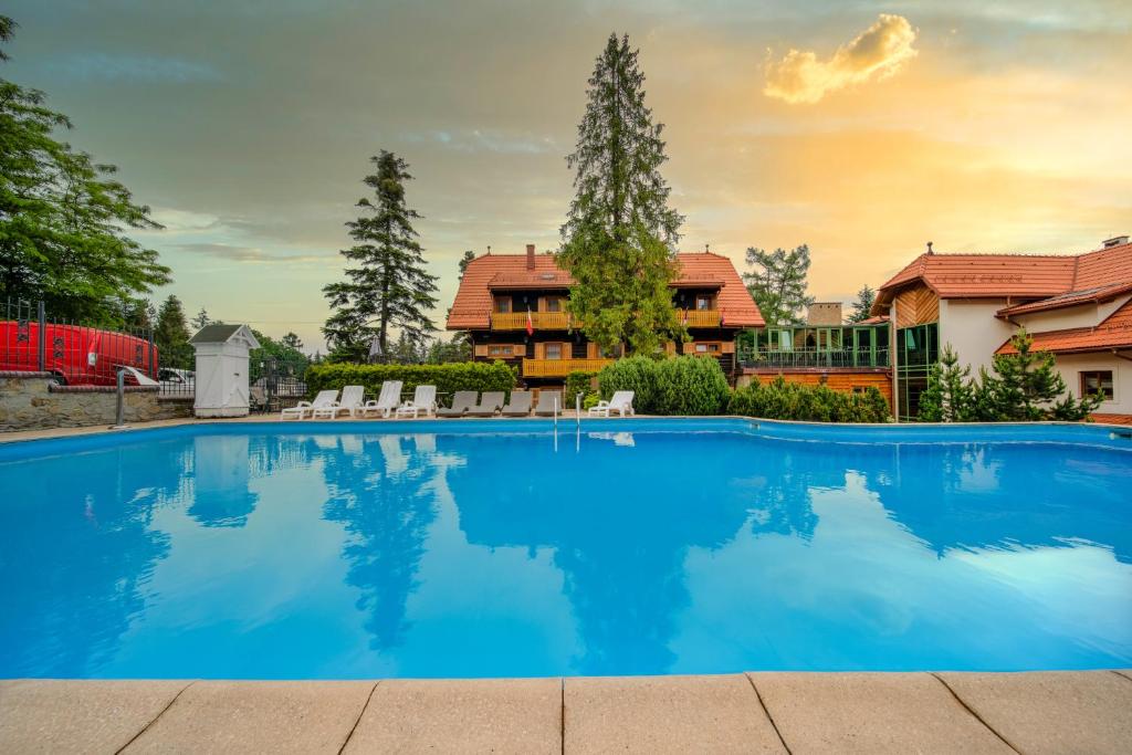 a large blue swimming pool in front of a house at Hotel Modrzewiówka in Lanckorona
