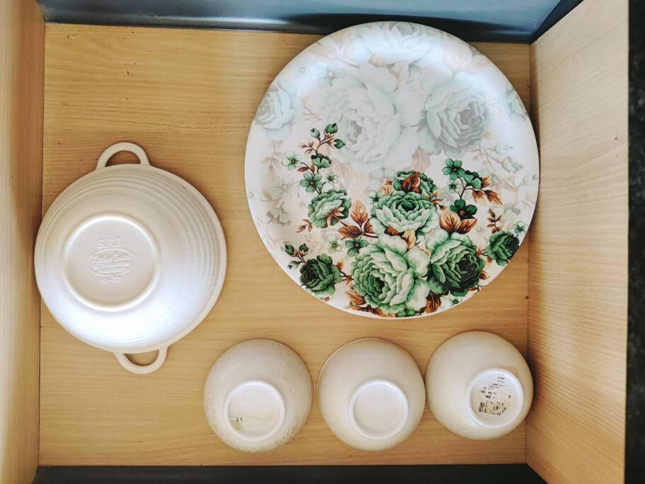 a plate and a bowl on a wooden shelf at Paris Suite By Hey Studio's in Ghaziabad