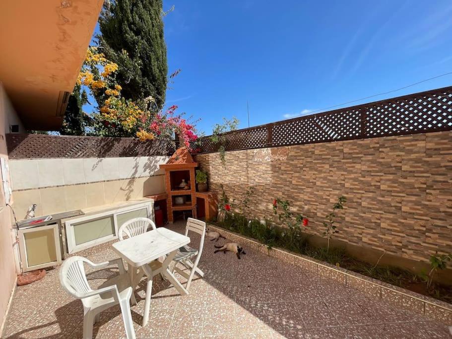 a patio with a table and chairs and a brick wall at Duplex a Sidi Bouzid in Sidi Bouzid