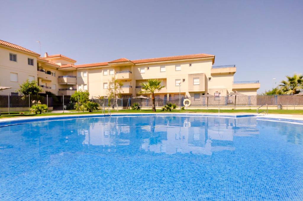 una gran piscina azul frente a un edificio en Apartamentos Sanlúcar & Doñana, en Sanlúcar de Barrameda