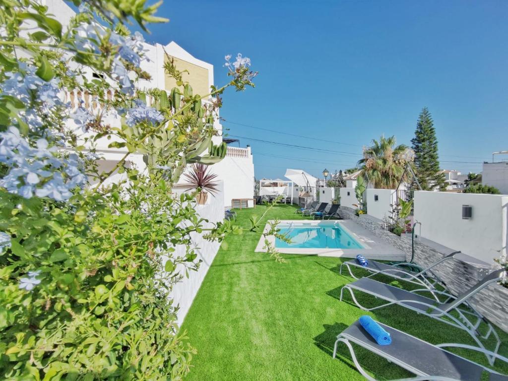 a backyard with a swimming pool and green grass at Casa Higuera in Nerja