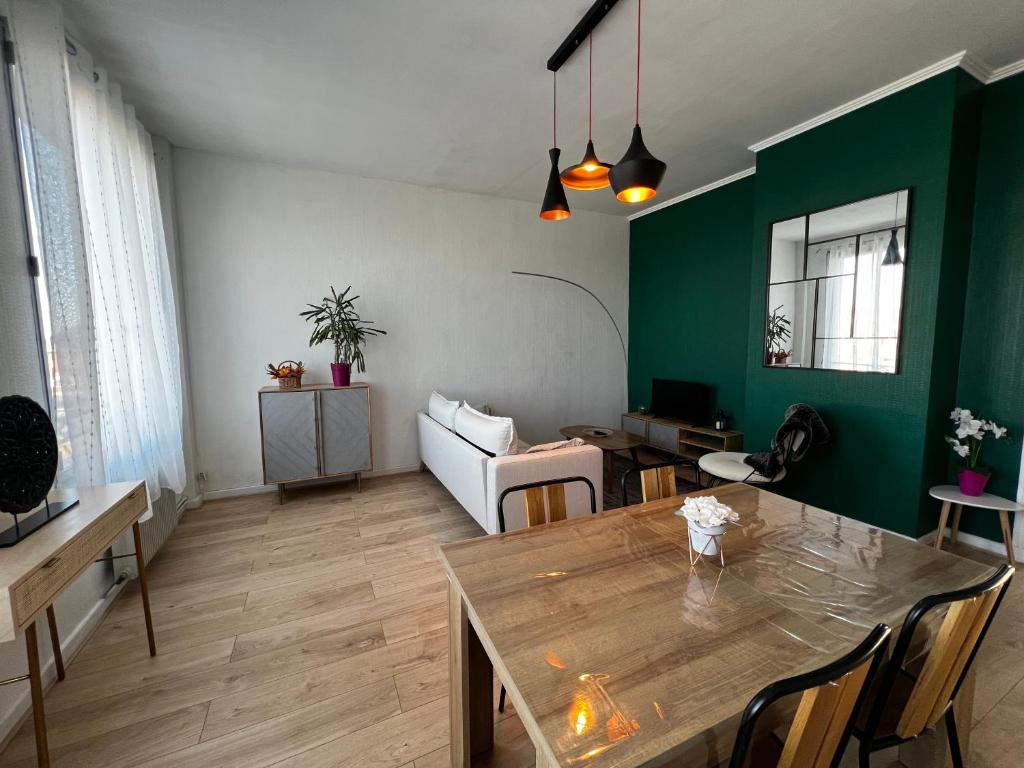 een woonkamer met een tafel en een groene muur bij Douai 2: joli appartement face à la gare in Douai