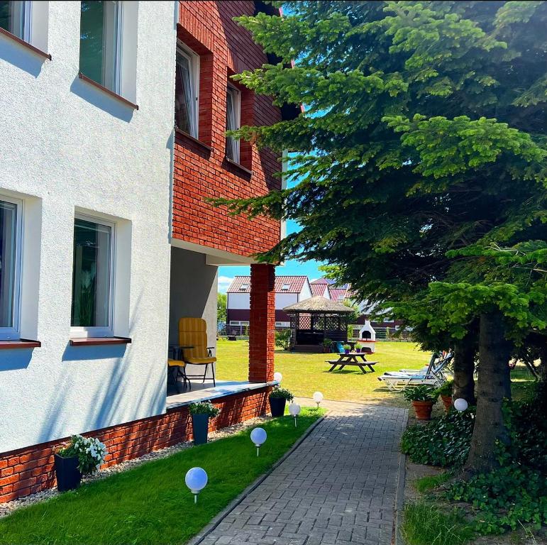 a building with a tree next to a sidewalk at Apartamenty Ostoja in Łeba