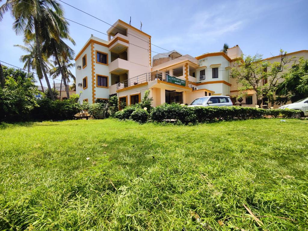 a house with a green lawn in front of it at Hotel Surya Greens in Puri