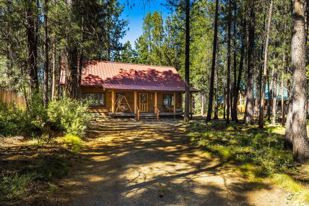 una cabaña en el bosque con un camino de tierra delante en Red Pines Log Cabin, en Sunriver