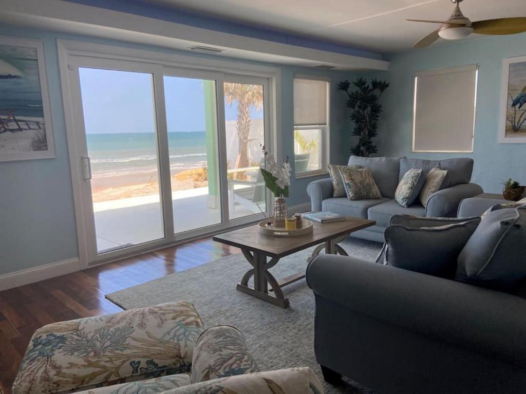 Sala de estar con sofá, mesa y el océano en Manatee Manor Beachfront Retreat, en Daytona Beach