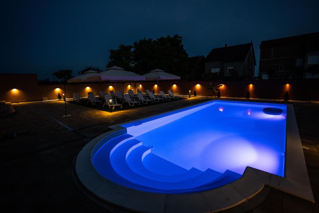 a swimming pool lit up at night at Villa Biser Dunava in Vukovar