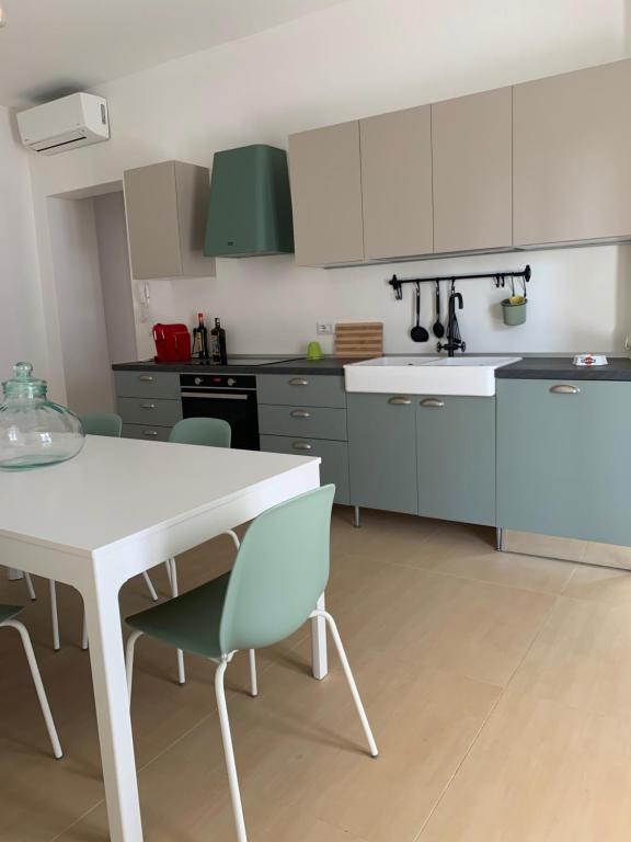 una cucina con tavolo bianco e sedie verdi di CONTINOWINES a Lequile