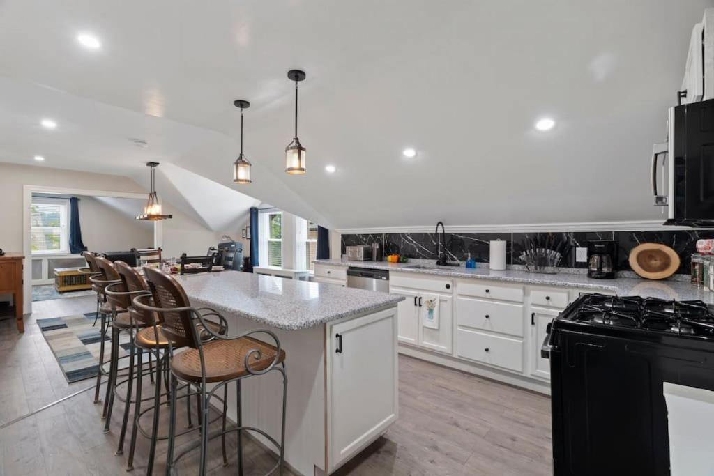 a kitchen with white cabinets and a island with bar stools at Spacious Home King Beds Gym Deck Games Parking AC in Narberth
