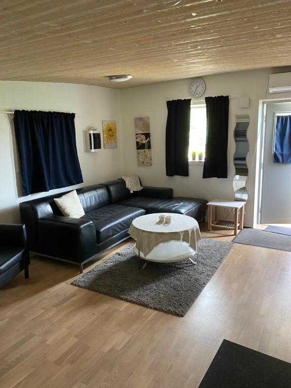 a living room with a black leather couch and a table at Idyliska boende mitt på Öland in Färjestaden