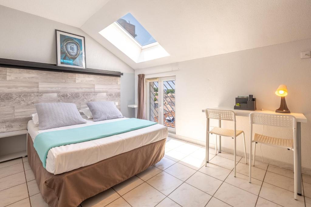 a bedroom with a bed and a table and chairs at Résidence Les Cordeliers in Avignon