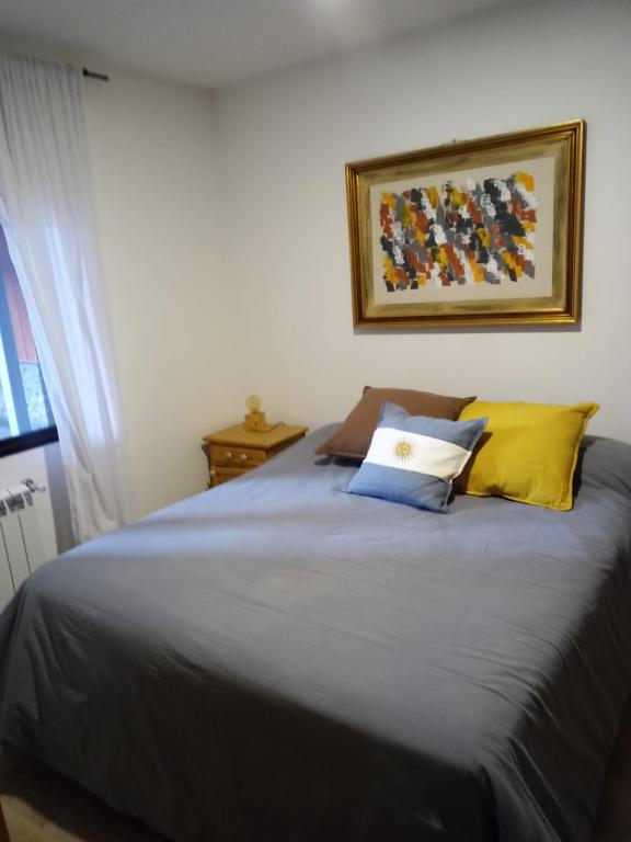 uma cama com duas almofadas e uma fotografia na parede em Hermoso Departamento Céntrico en San Martin de los Andes em San Martín de los Andes