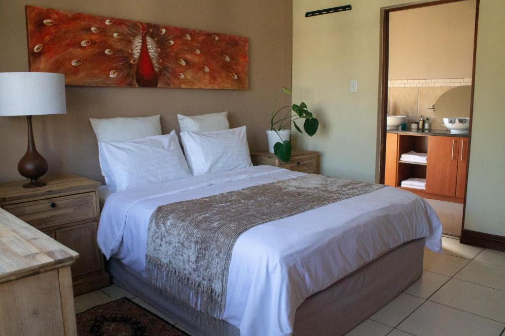 a bedroom with a large bed with white sheets at 21 at Melody in Hartbeespoort