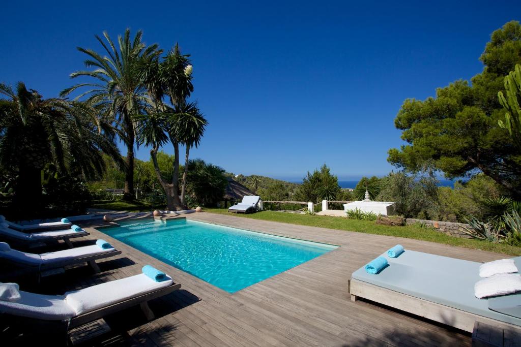 a swimming pool with chaise lounge chairs next to a house at Can Lib in Sant Josep de sa Talaia